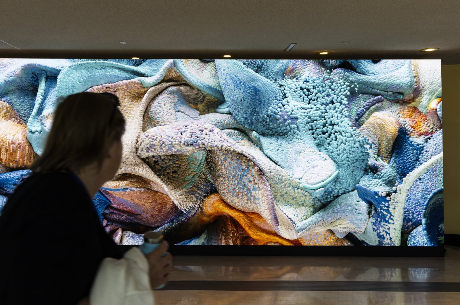 A person walks past an AI-generated video art installation entitled &#039;Large Nature Model: Coral&#039; by artist Refik Anadol at the U.N. headquarters in New York, U.S., Sept. 19, 2024. (EPA Photo)