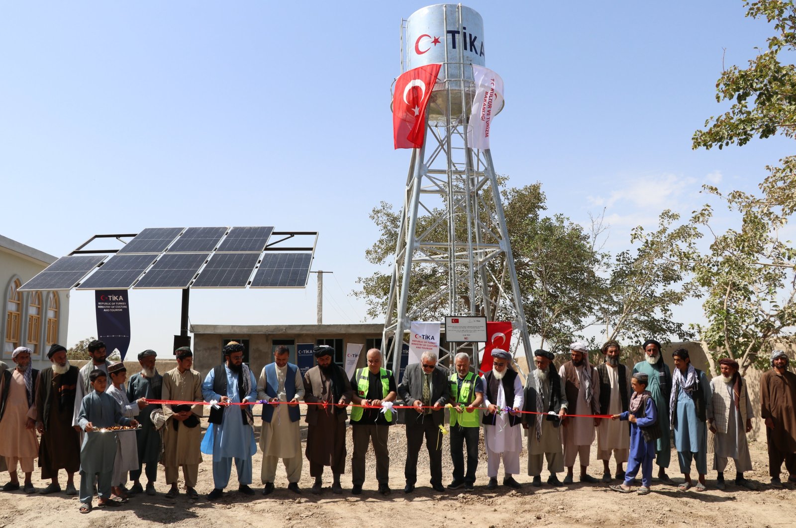 Participants cut the ribbon to inaugurate the TIKA-built galvanized water tank, Balkh, Afghanistan, Sept. 24, 2024. (AA Photo)