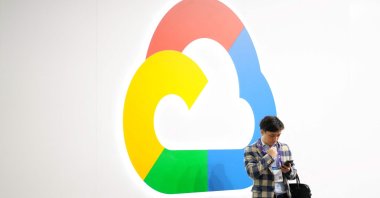 A man uses his phone next to Google Cloud's logo at the Mobile World Congress (MWC), the telecom industry's biggest annual gathering, Barcelona, Spain, Feb. 27, 2024. (AFP Photo)