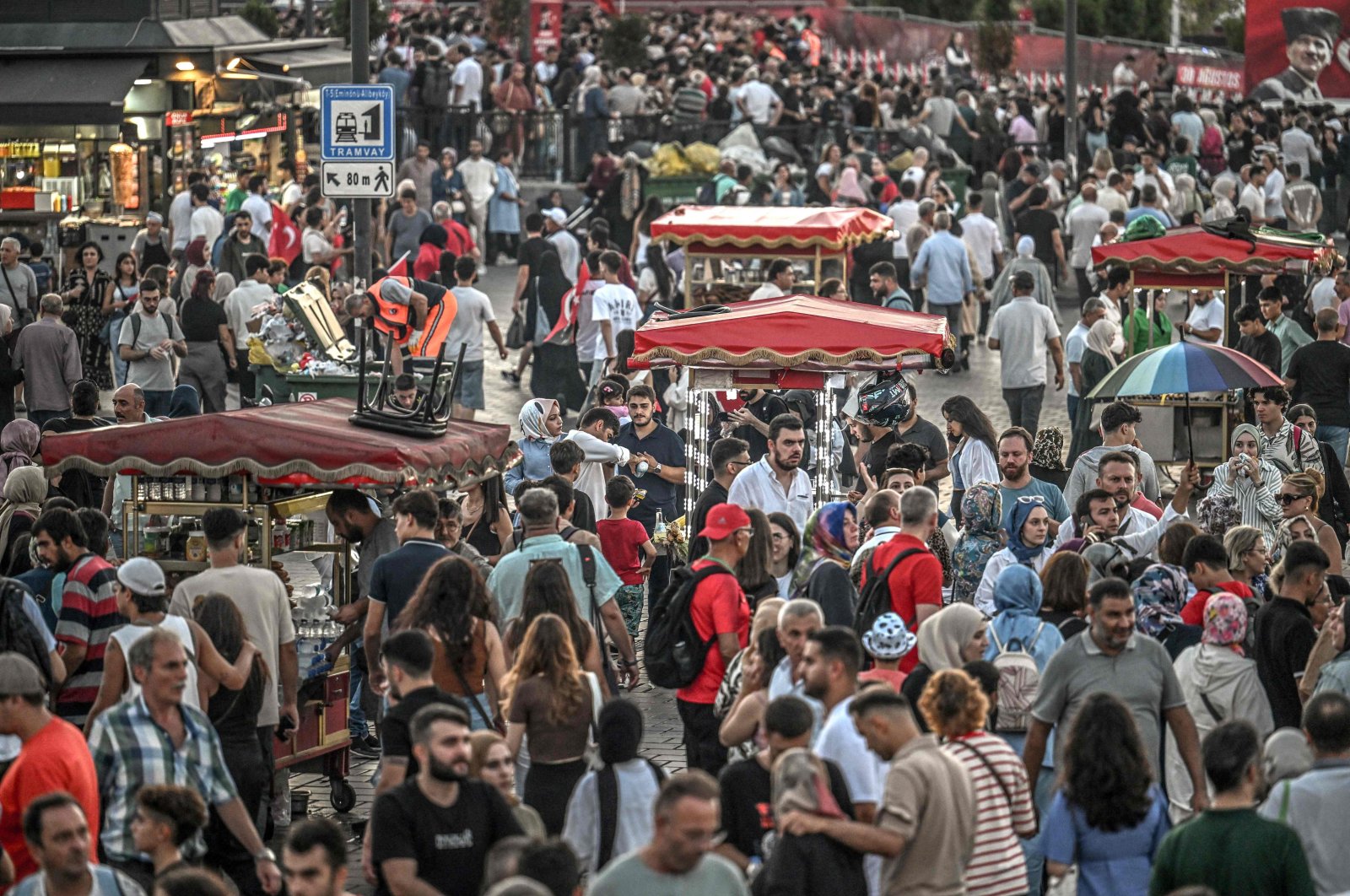 Street vendors sell corn and traditional Turkish bakery &quot;simit&quot; as people pass by their stands in the famed Eminönü neighborhood of Istanbul, Türkiye, Aug. 30, 2024. (AFP Photo)