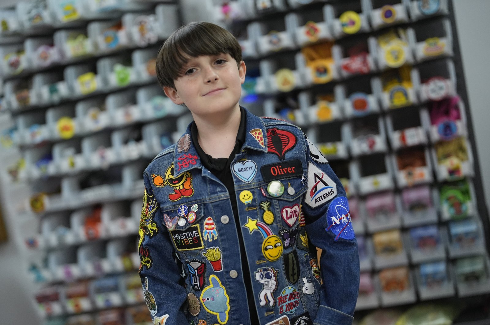 Oliver Burkhardt, 13, stands in front of trays of patches inside the offices of the Oliver Patch Project, Florida, U.S., Sept. 4, 2024. (AP Photo)