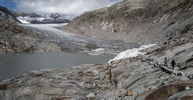 People walk next to the Rhone Glacier and its glacial lake (L), formed by the melting of the glacier due to global warming, near Gletsch, in the Swiss Alps, Switzerland, Sept. 30, 2024. (AFP Photo)