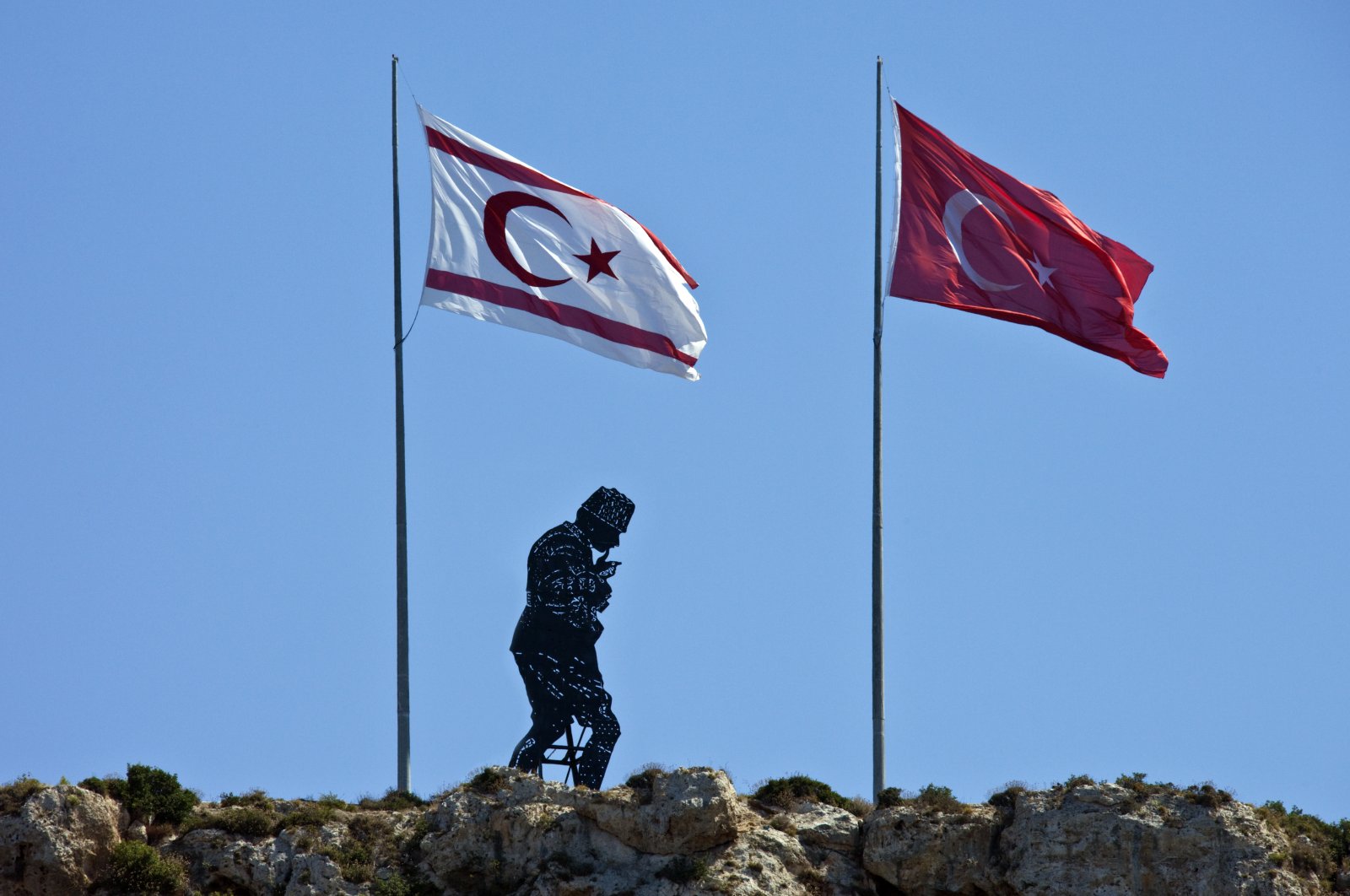 A hillside monument dedicated to Mustafa Kemal Atatürk, the founder of modern Türkiye (1881-1938), between flags of the Turkish Republic of Northern Cyprus (TRNC) and Türkiye, Girne (Kyrenia), TRNC, Oct. 1, 2010. (Getty Images Photo)