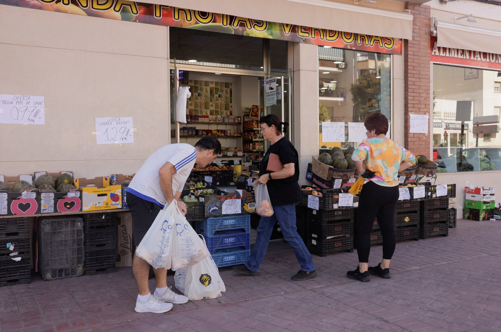 A salesperson watches as a customer buys peaches outside a store in Ronda, Spain, Sept. 30, 2024. (Reuters Photo)