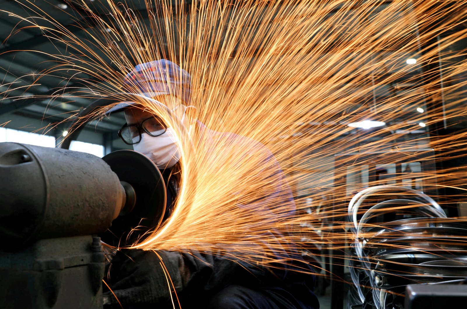 A worker wearing a face mask works on a production line manufacturing bicycle steel rims at a factory in Hangzhou, Zhejiang province, China, March 2, 2020. (Reuters Photo)