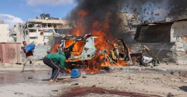 Displaced Palestinians douse a burning car with water after it was hit in an Israeli strike in Khan Younis, southern Gaza Strip, Palestine, Oct. 1, 2024. (AFP Photo)