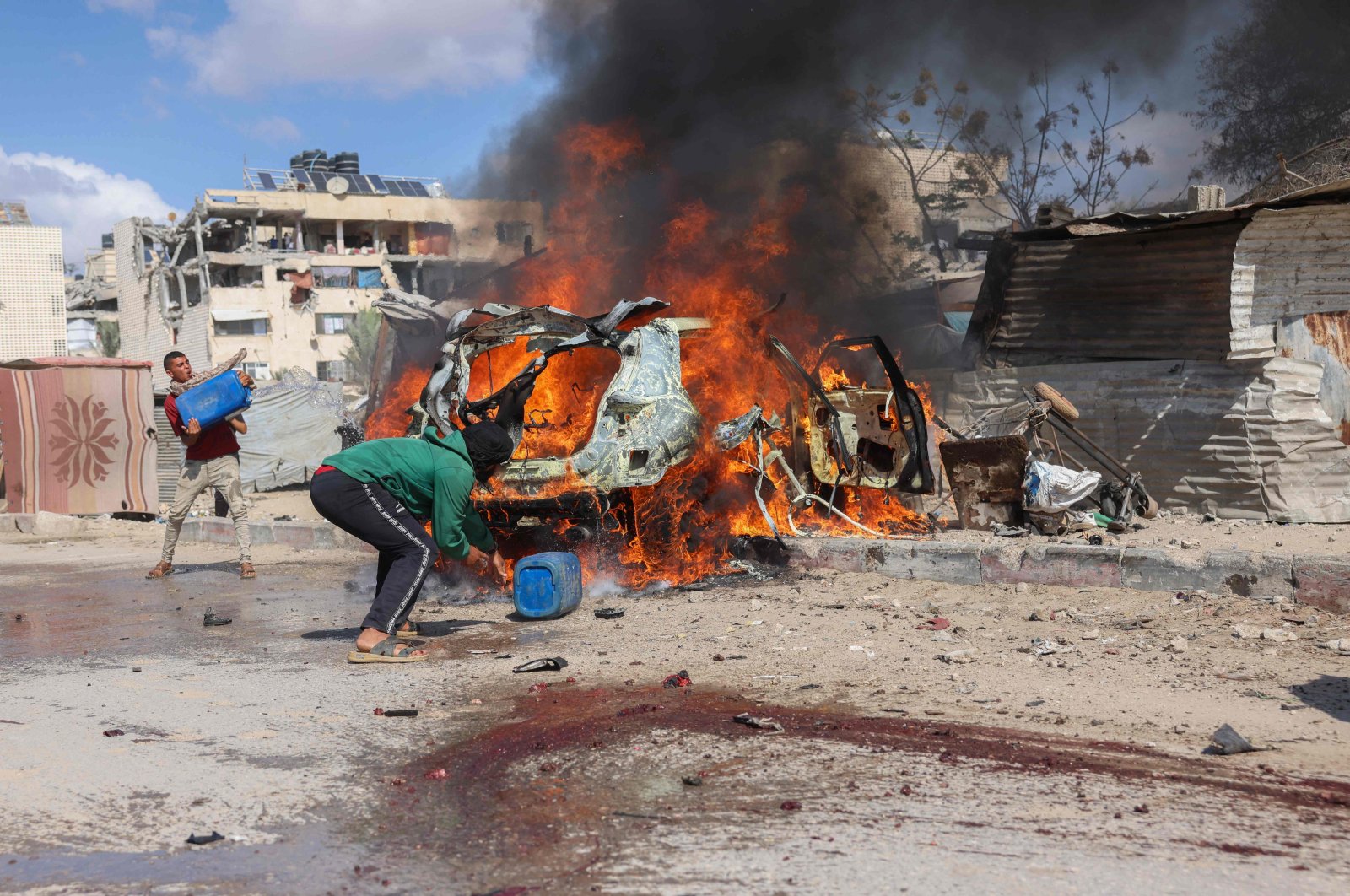 Displaced Palestinians douse a burning car with water after it was hit in an Israeli strike in Khan Younis, southern Gaza Strip, Palestine, Oct. 1, 2024. (AFP Photo)