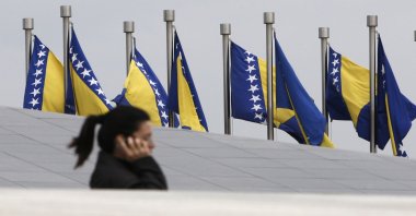A Bosnian woman passes by Bosnian state flags in Sarajevo, Bosnia-Herzegovina, Oct. 4, 2010. (AP Photo)