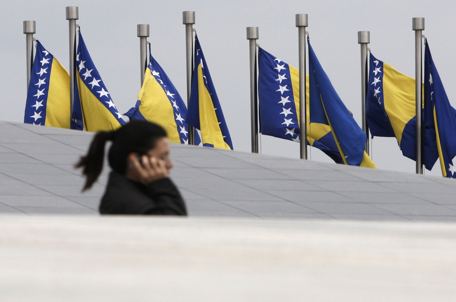 A Bosnian woman passes by Bosnian state flags in Sarajevo, Bosnia-Herzegovina, Oct. 4, 2010. (AP Photo)