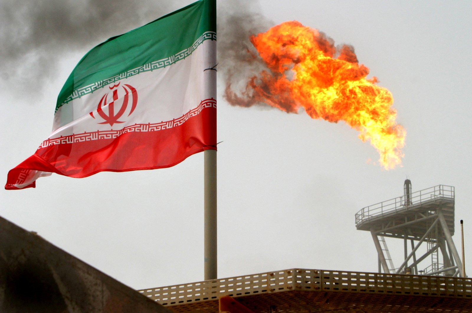 A gas flare on an oil production platform is seen alongside an Iranian flag in the Gulf, July 25, 2005. (Reuters File Photo)