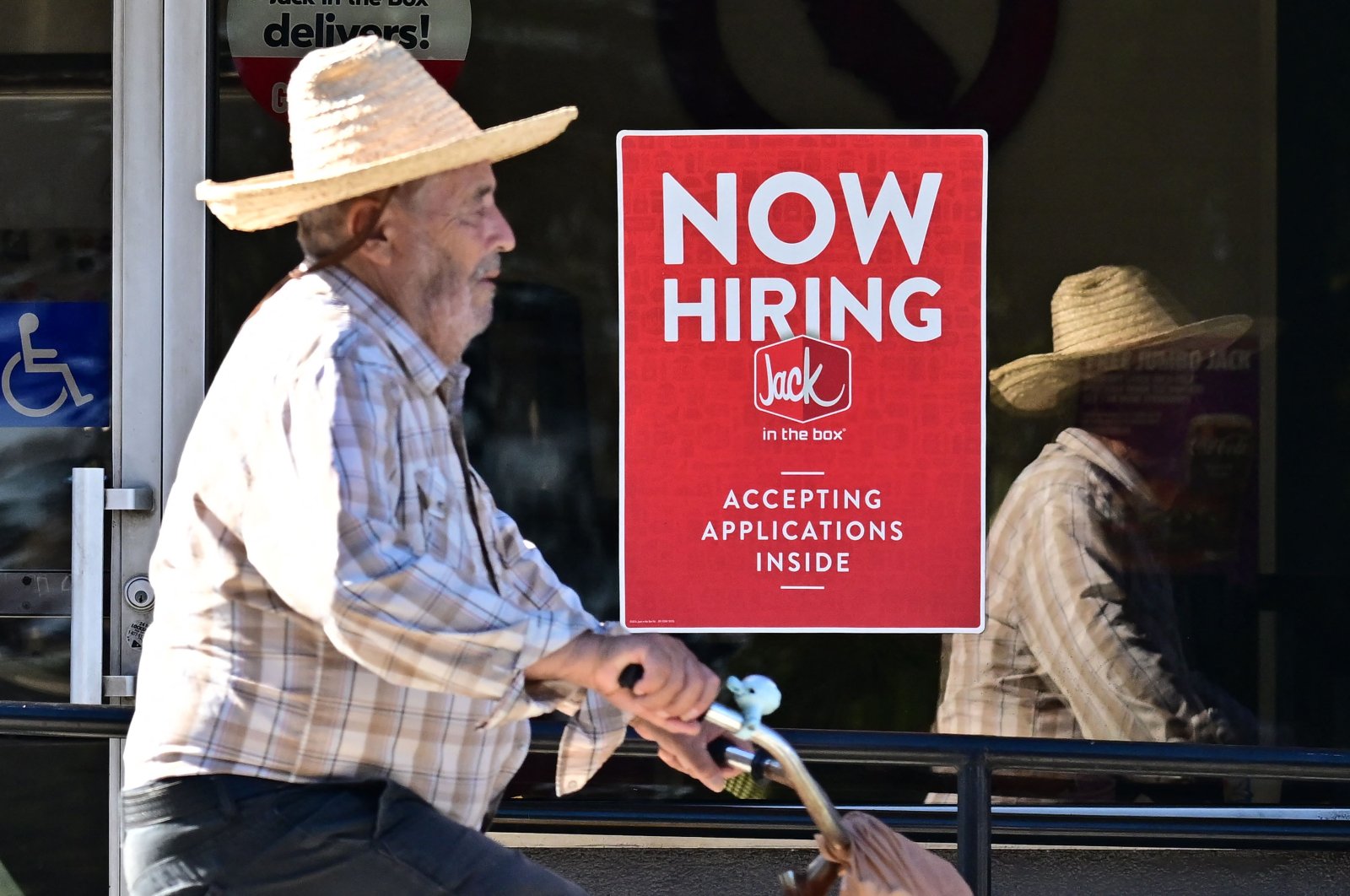 A cyclist rides past a &quot;Now Hiring&quot; sign posted on a business storefront in San Gabriel, California, U.S., Aug. 21, 2024. (AFP Photo)