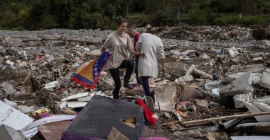A girl carries a Bosnian flag as she stands next to her destroyed house after floods and landslides in a village of Trusina, Bosnia and Herzegovina, Oct. 6, 2024. (Reuters Photo)