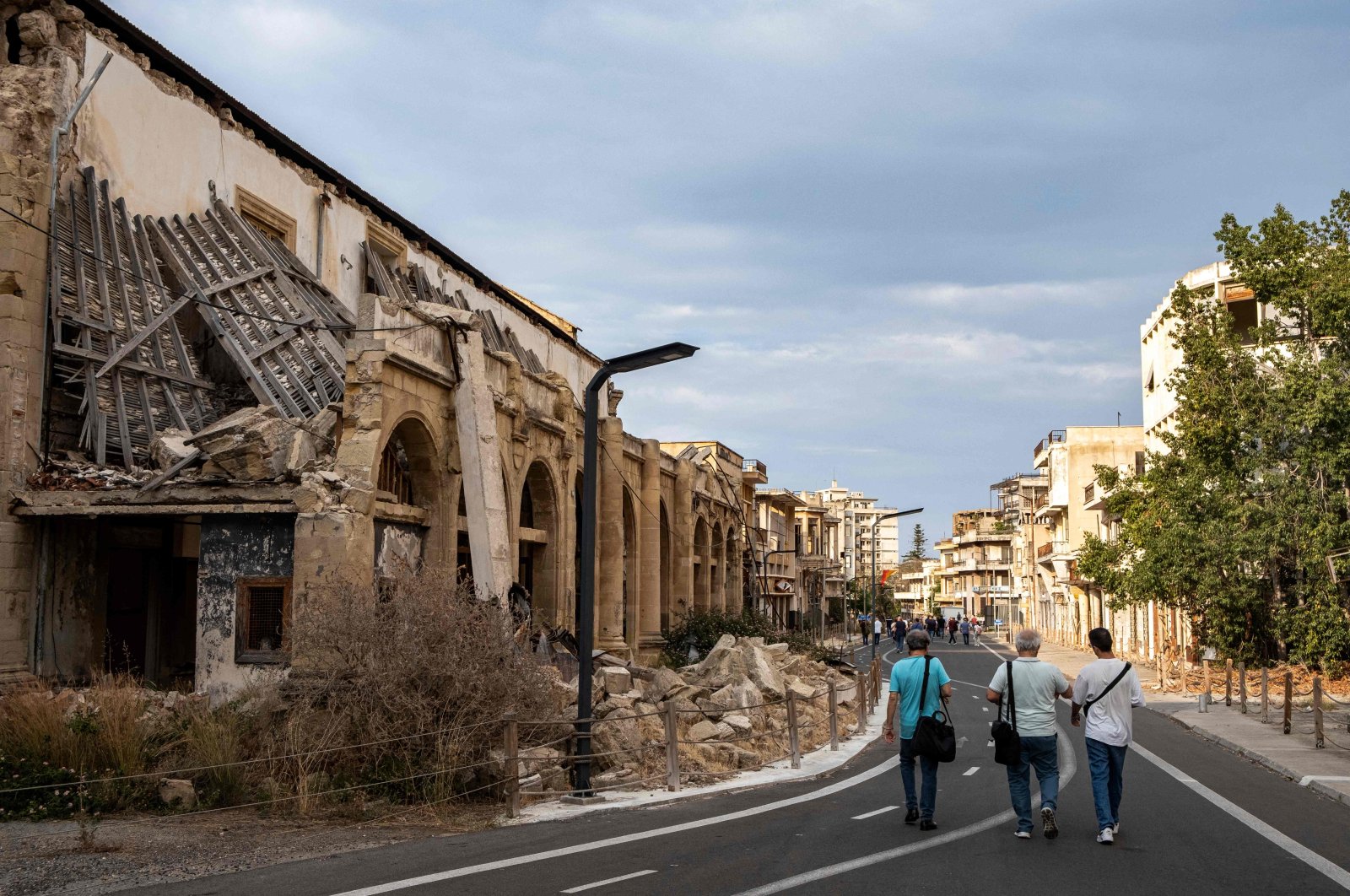 Journalists walk during an organized tour past partially collapsed abandoned buildings in Varosha, in the fenced-off area of Famagusta, TRNC, June 19, 2023. (AFP Photo)