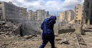 A woman walks past a crater where a collapsed building stood following an overnight Israeli air strike on the neighborhood of Kafaat in Beirut&#039;s southern suburbs, Lebanon, Oct. 7, 2024. (AFP Photo)