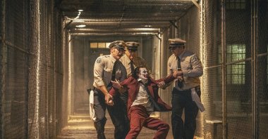 Joaquin Phoenix (foreground C) and Brendan Gleeson (background C) in a scene from &quot;Joker: Folie a Deux.&quot; (Warner Bros. via AP Photo)