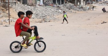 Children ride a bicycle across a war-devastated street in Gaza City, Palestine, Oct. 2, 2024. (AFP Photo)