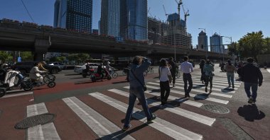 People cross a road in the business district in Beijing, China, Oct. 8, 2024. (AFP Photo)