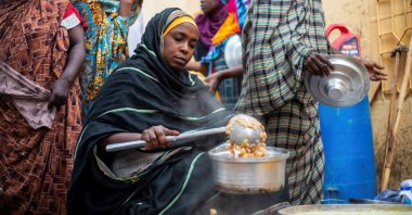 A Sudanese woman from a community kitchen distributes meals for people affected by conflict and extreme hunger, in Omdurman, Sudan, Aug. 22, 2024. (Reuters Photo)