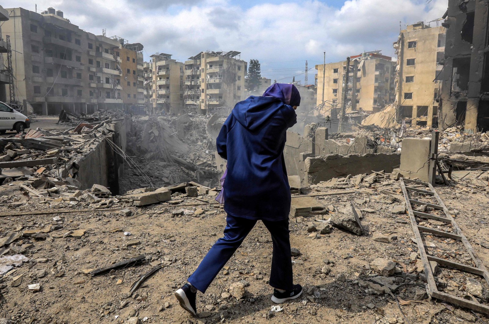 A woman walks past a crater where a collapsed building stood following an overnight Israeli air strike on the neighborhood of Kafaat in Beirut&#039;s southern suburbs, Lebanon, Oct. 7, 2024. (AFP Photo)