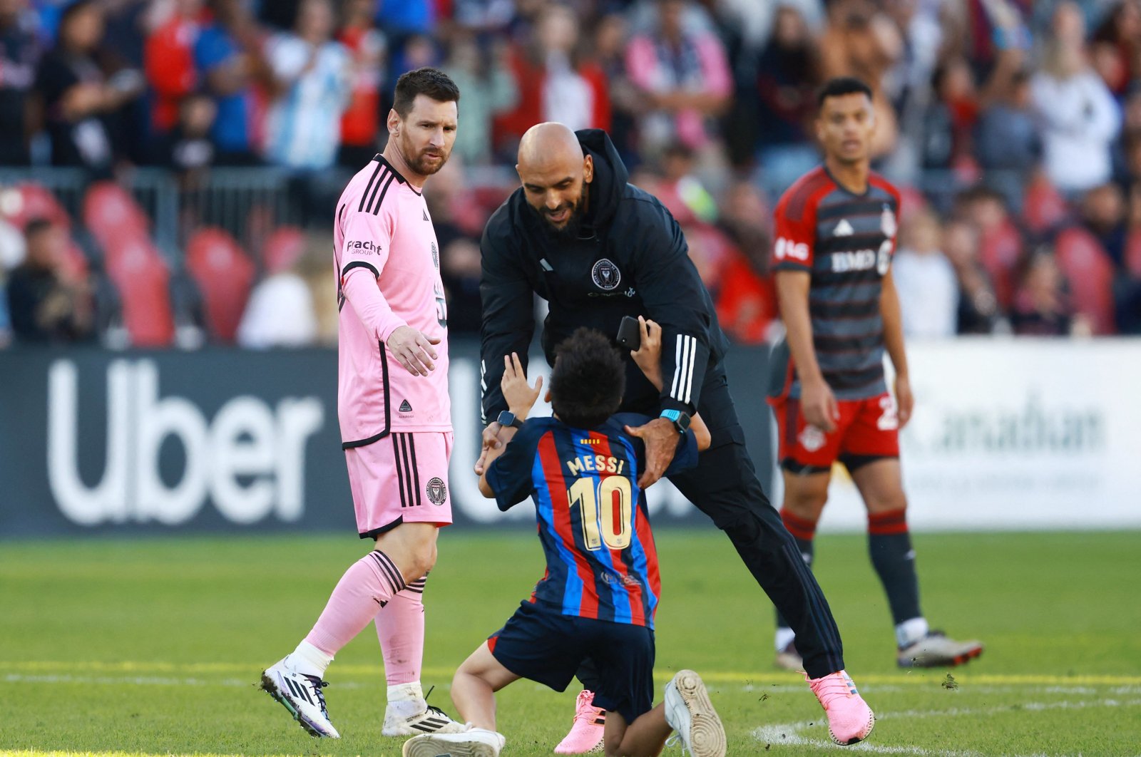 Inter Miami&#039;s Lionel Messi (L) looks on as his security guard grabs a young child who ran onto the field during a game against Toronto FC at BMO Field, Toronto, Ontario, Canada, Oct. 5, 2024. (AFP Photo)