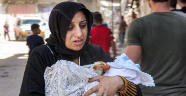 An evacuating woman walks carrying an infant child in the Jabalia camp in the northern Gaza Strip, Palestine, Oct. 9, 2024. (AFP Photo)