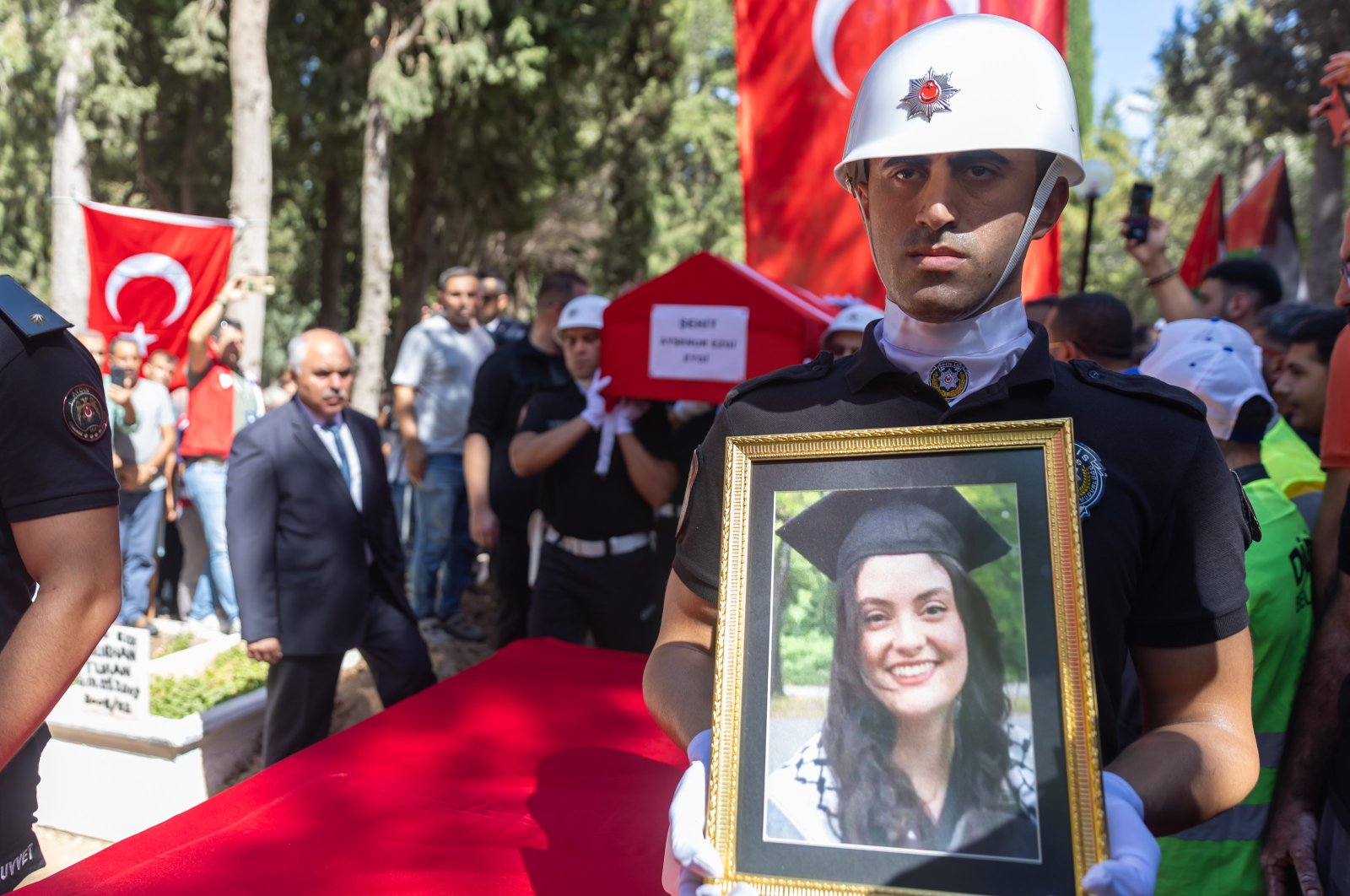 A police officer holds a portrait of Ayşenur Ezgi Eygi during her funeral procession at a cemetery in Didim, Aydın, Türkiye, Sept. 14, 2024. (AA Photo)