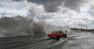 A car drives past waves crashing against the Malecon promenade in Havana due to the passage of Hurricane Milton, Cuba, Oct. 9, 2024. (AFP Photo)