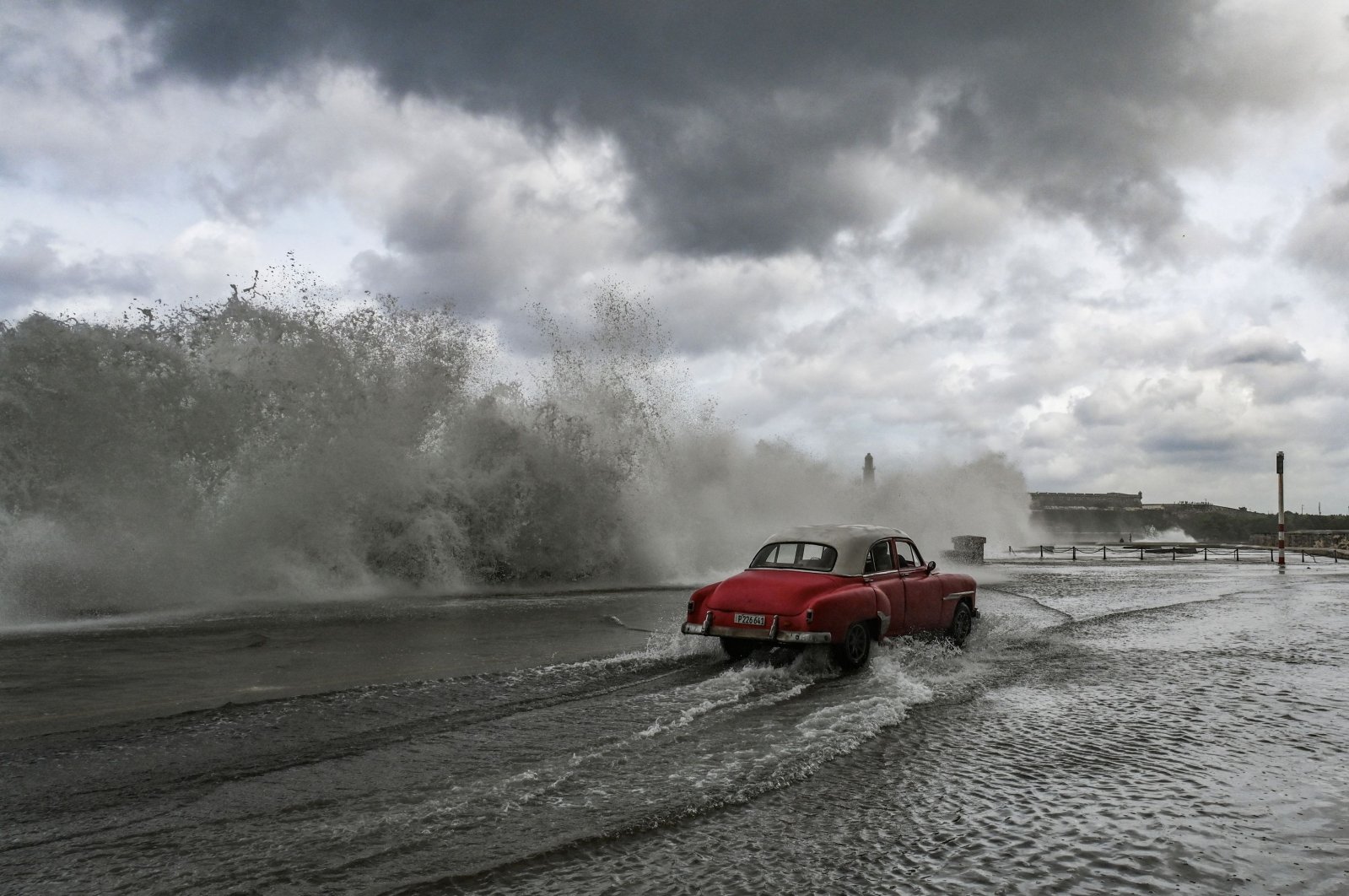 A car drives past waves crashing against the Malecon promenade in Havana due to the passage of Hurricane Milton, Cuba, Oct. 9, 2024. (AFP Photo)