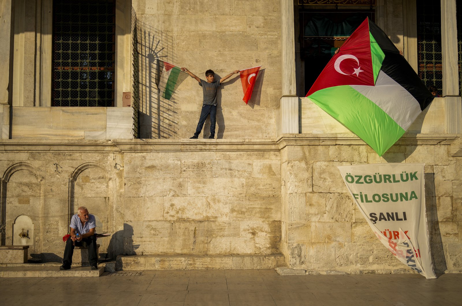 A youngster holds Palestinian and Turkish flags during a protest against Israel outside the historic Fatih Mosque, Istanbul, Türkiye, Aug. 25, 2024. (AP Photo)