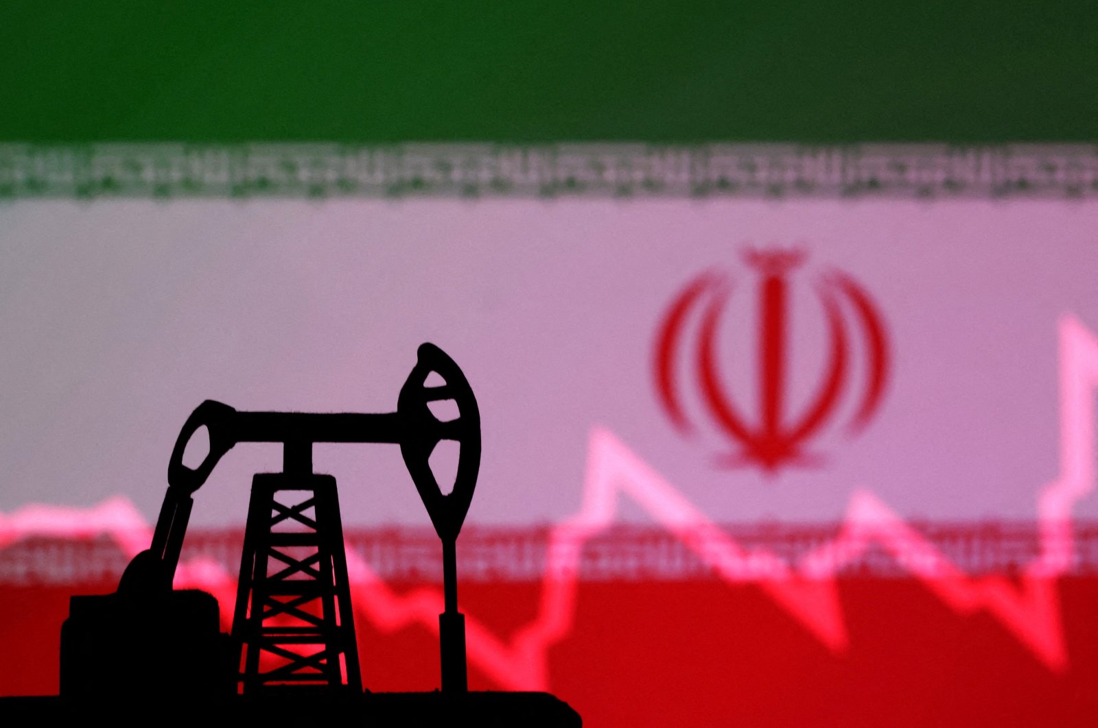 The Iranian flag with a stock graph and an oil pump jack miniature model are seen in this illustration taken Oct. 9, 2023. (Reuters Photo)