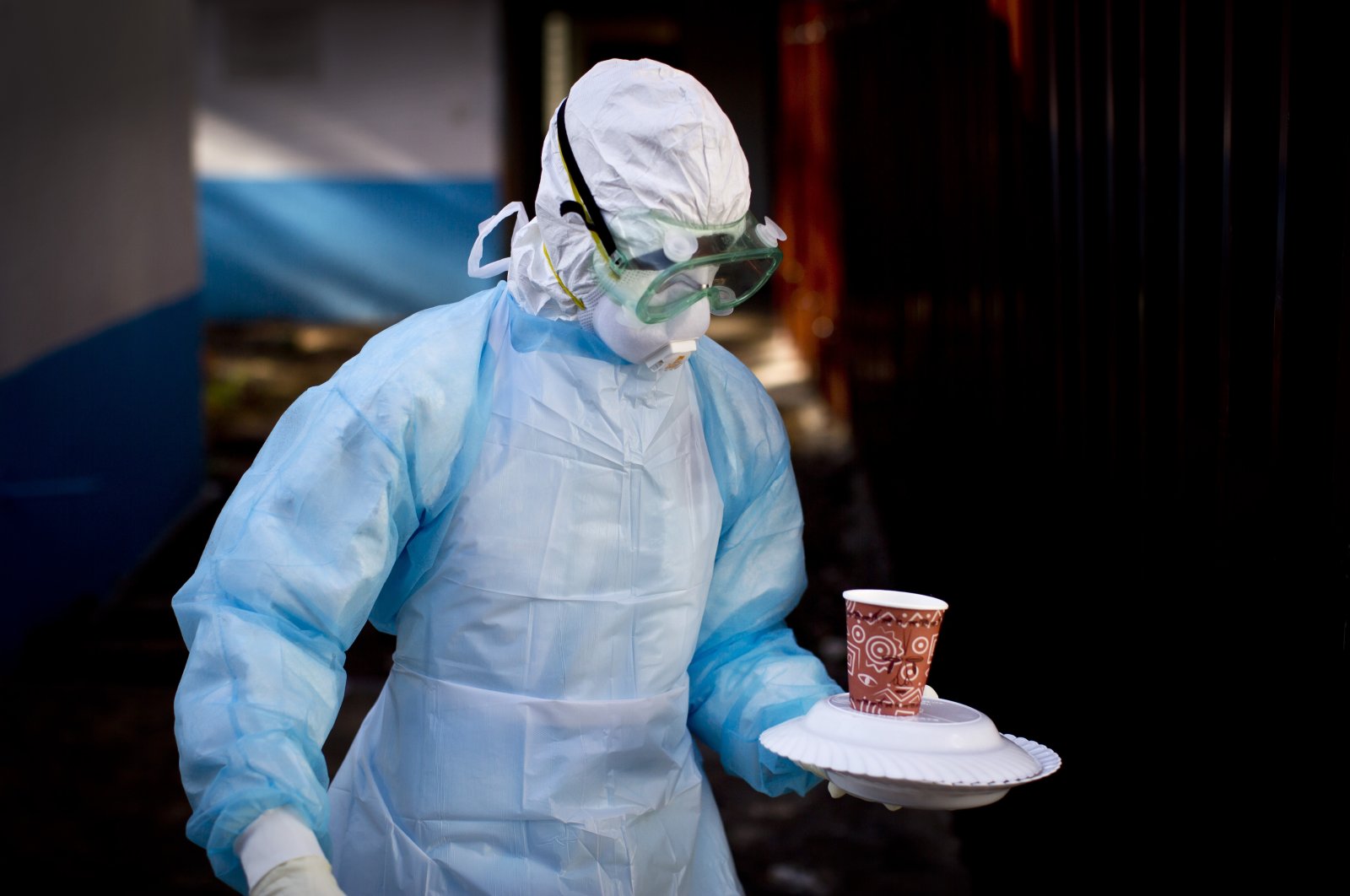 A medical worker from the Infection Prevention and Control unit wearing full protective equipment carries a meal to an isolation tent housing a man being quarantined after coming into contact in Uganda with a carrier of the Marburg virus, at the Kenyatta National Hospital, Nairobi, Kenya, Oct. 8, 2014. (AP Photo)