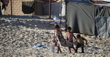 Displaced Palestinian children carry a crate back to their tent at a makeshift camp on the beach of Gaza City, Palestine, Oct. 13, 2024. (AFP Photo)