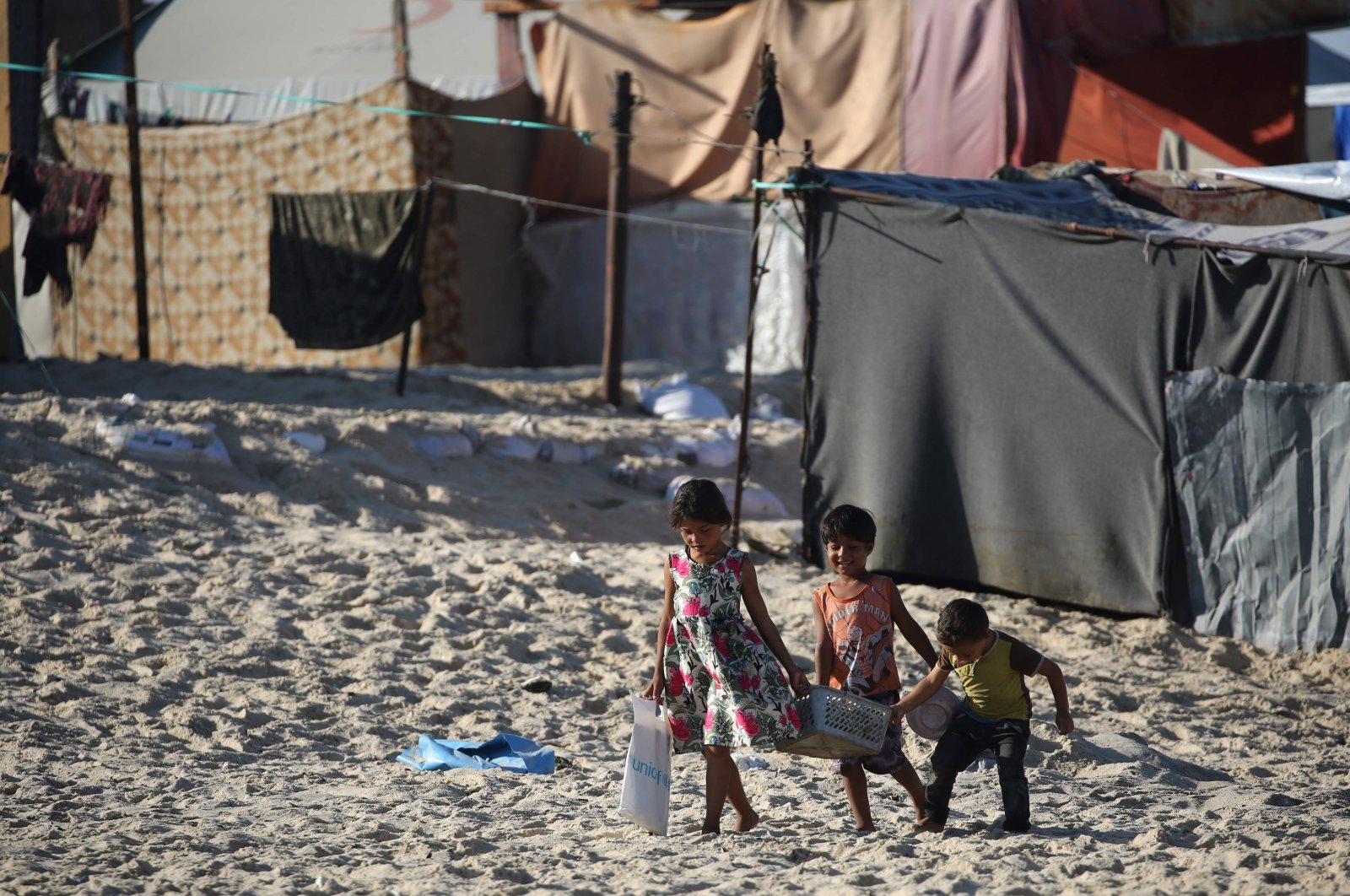 Displaced Palestinian children carry a crate back to their tent at a makeshift camp on the beach of Gaza City, Palestine, Oct. 13, 2024. (AFP Photo)