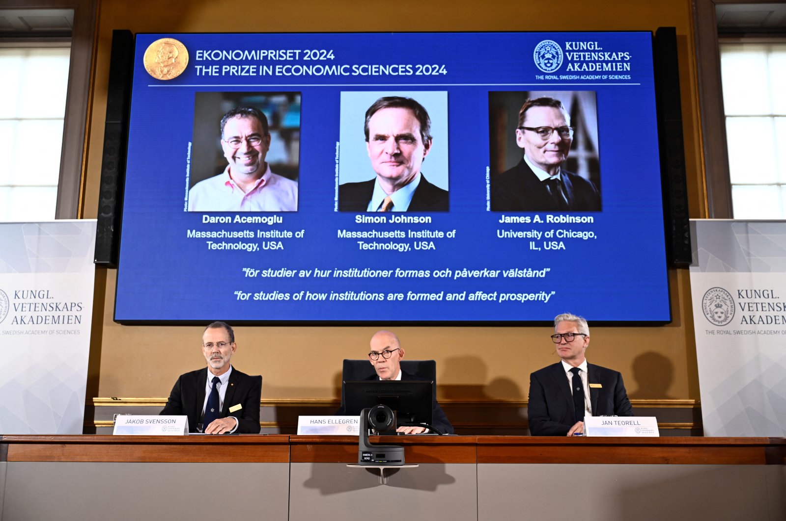 The Nobel Economics Prize is awarded to Daron Acemoğlu, Simon Johnson and James A Robinson, seen on screen during a press meeting at the Royal Swedish Academy of Sciences in Stockholm, Sweden, Oct. 14, 2024. (Reuters Photo)