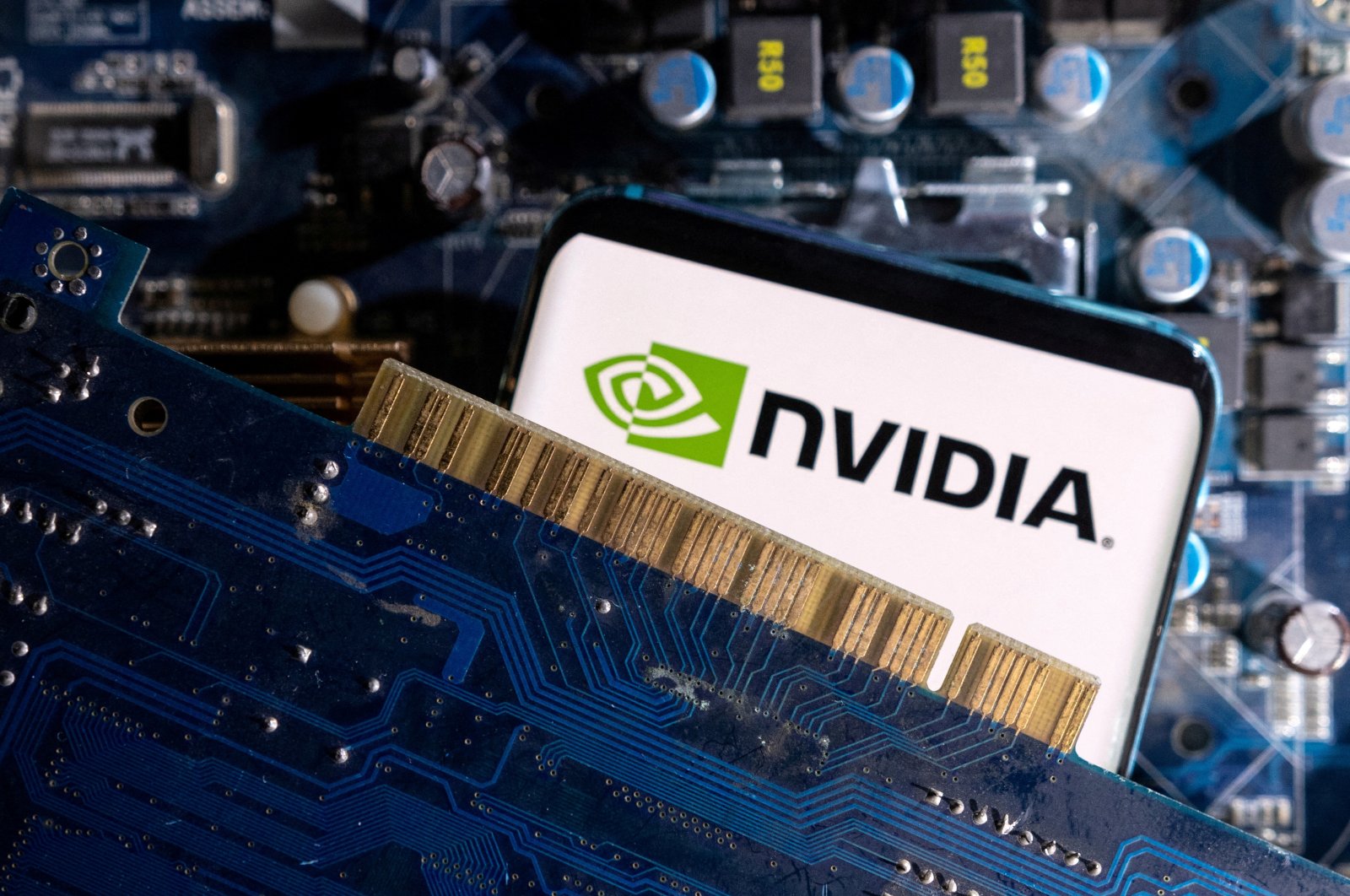 A smartphone with a displayed Nvidia logo is placed on a computer motherboard in this illustration taken March 6, 2023. (Reuters Photo)