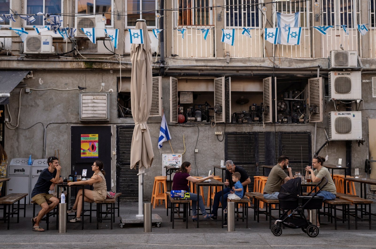 People sit at an outdoor restaurant where Israeli flags are displayed in Tel Aviv, Israel, July 12, 2024. (Reuters Photo)