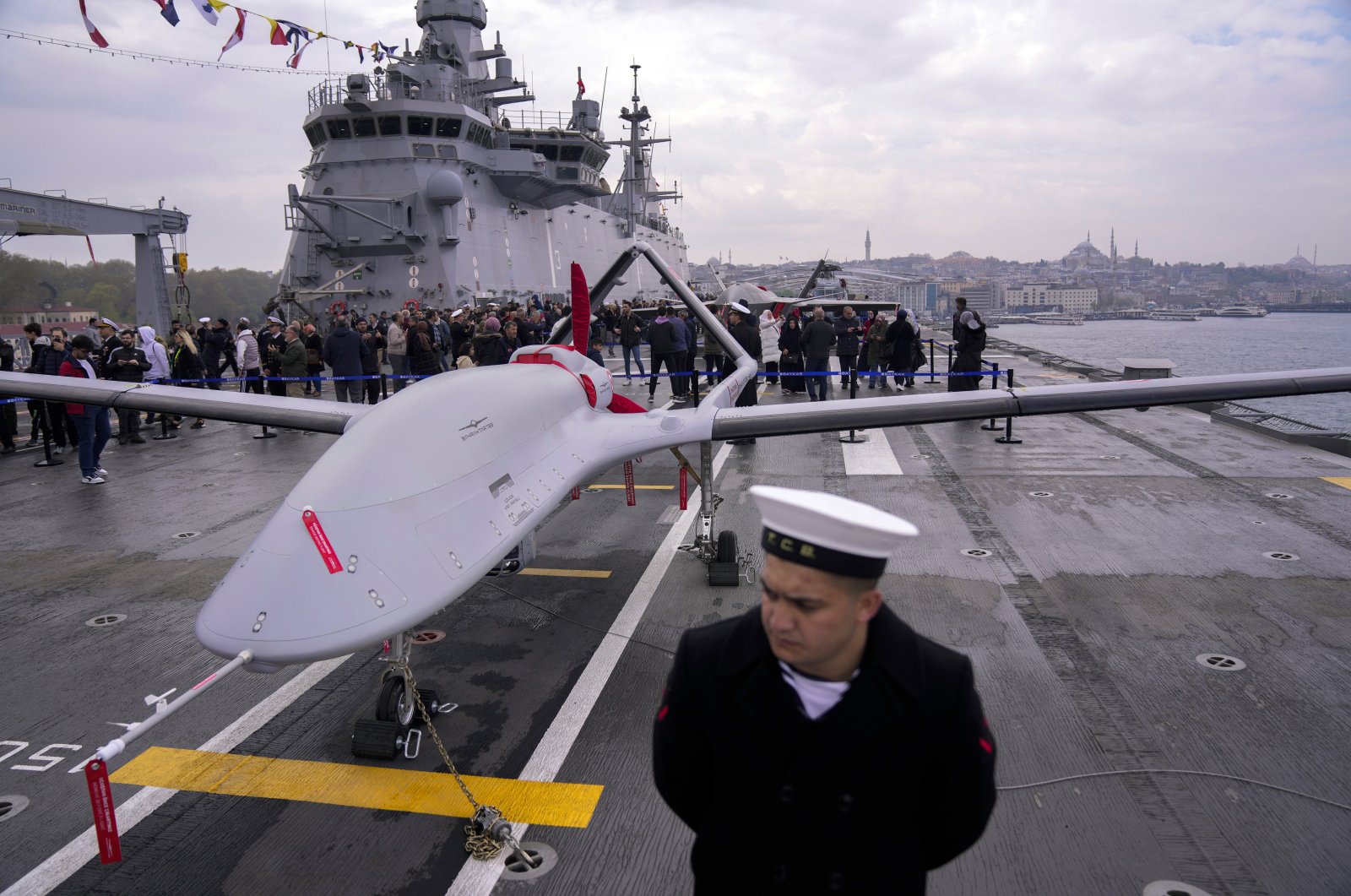 A naval soldier stands next to an unmanned combat aerial vehicle (UCAV) Bayraktar TB3 on board the Turkish amphibious assault ship TCG Anadolu L400, anchored in Istanbul, Türkiye, April 20, 2023. (AP Photo)