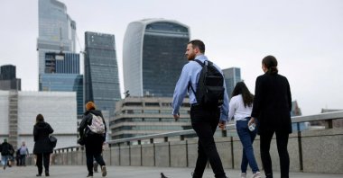 Commuters cross London Bridge in view of the City of London skyline, London, Britain, July 25, 2024. (Reuters Photo)