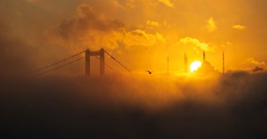 The sun rises behind the Grand Çamlıca Mosque as the July 15 Martyrs&#039; Bridge and the Bosporus are covered in fog, Istanbul, Türkiye, Oct. 16, 2024. (Reuters Photo)