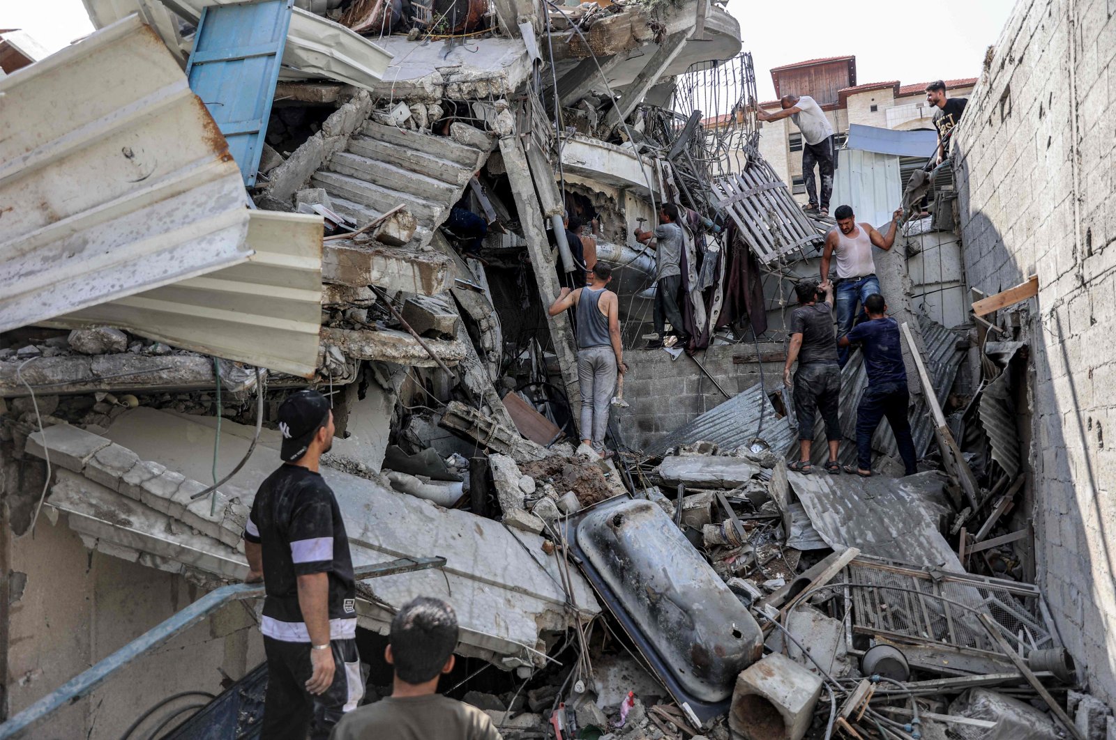 People gather outside a collapsed building as they attempt to extricate a man from underneath the rubble following Israeli bombardment in the Saftawi district in Jabalia, northern Gaza Strip, Palestine, Oct. 15, 2024. (AFP Photo)