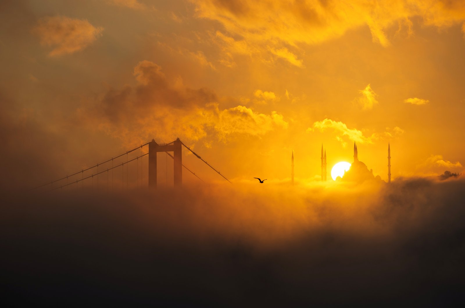 The sun rises behind the Grand Çamlıca Mosque as the July 15 Martyrs&#039; Bridge and the Bosporus are covered in fog, Istanbul, Türkiye, Oct. 16, 2024. (Reuters Photo)