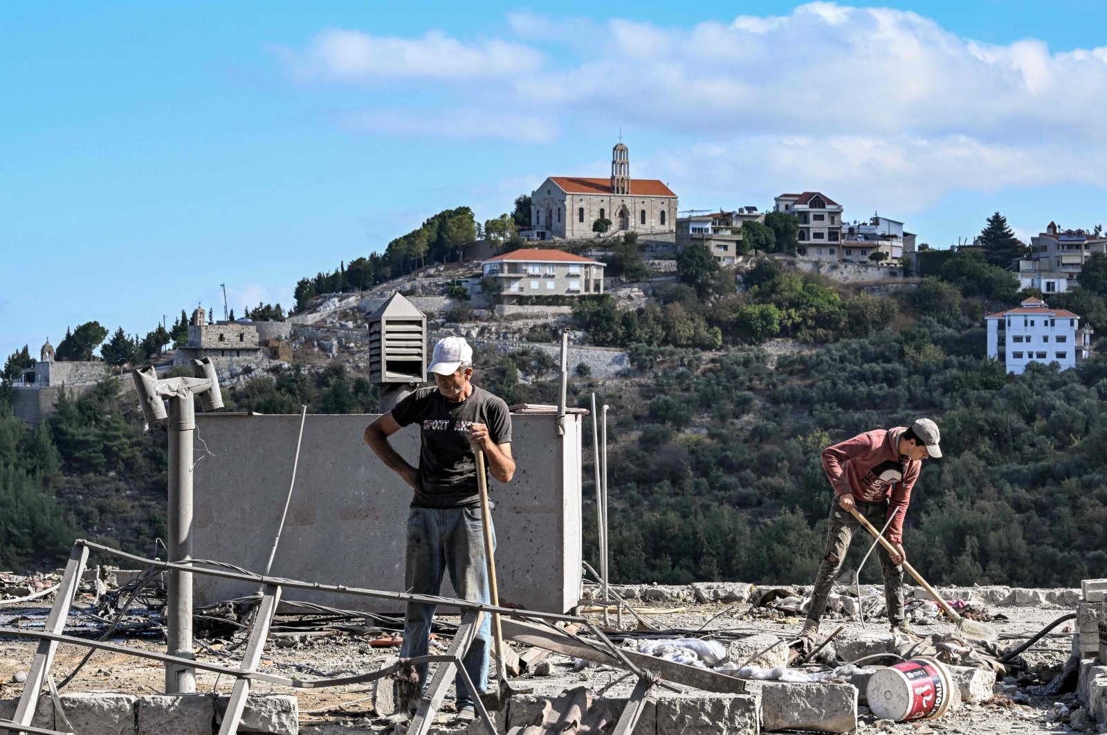 Men clear debris off the roof of a building by the site of a previous Israeli airstrike on the village of Aito, northern Lebanon, Oct. 15, 2024. (AFP Photo)