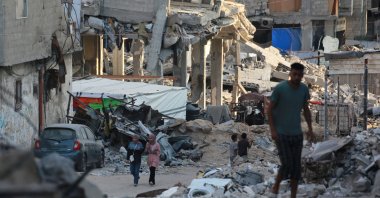 People walk past destroyed buildings in Khan Younis, southern Gaza Strip, Palestine, Oct. 17, 2024. (AFP Photo)