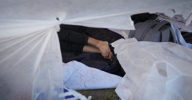 A migrant sleeps amidst hundreds who sought shelter outside an overcrowded asylum-seekers center in Ter Apel, northern Netherlands, Aug. 25, 2022. (AP Photo)