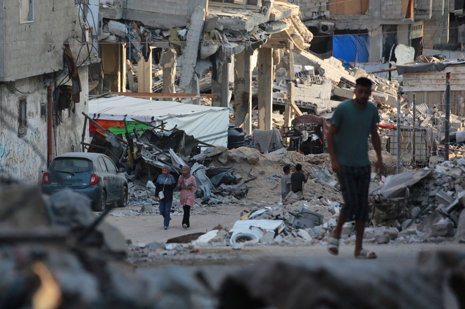 People walk past destroyed buildings in Khan Younis, southern Gaza Strip, Palestine, Oct. 17, 2024. (AFP Photo)