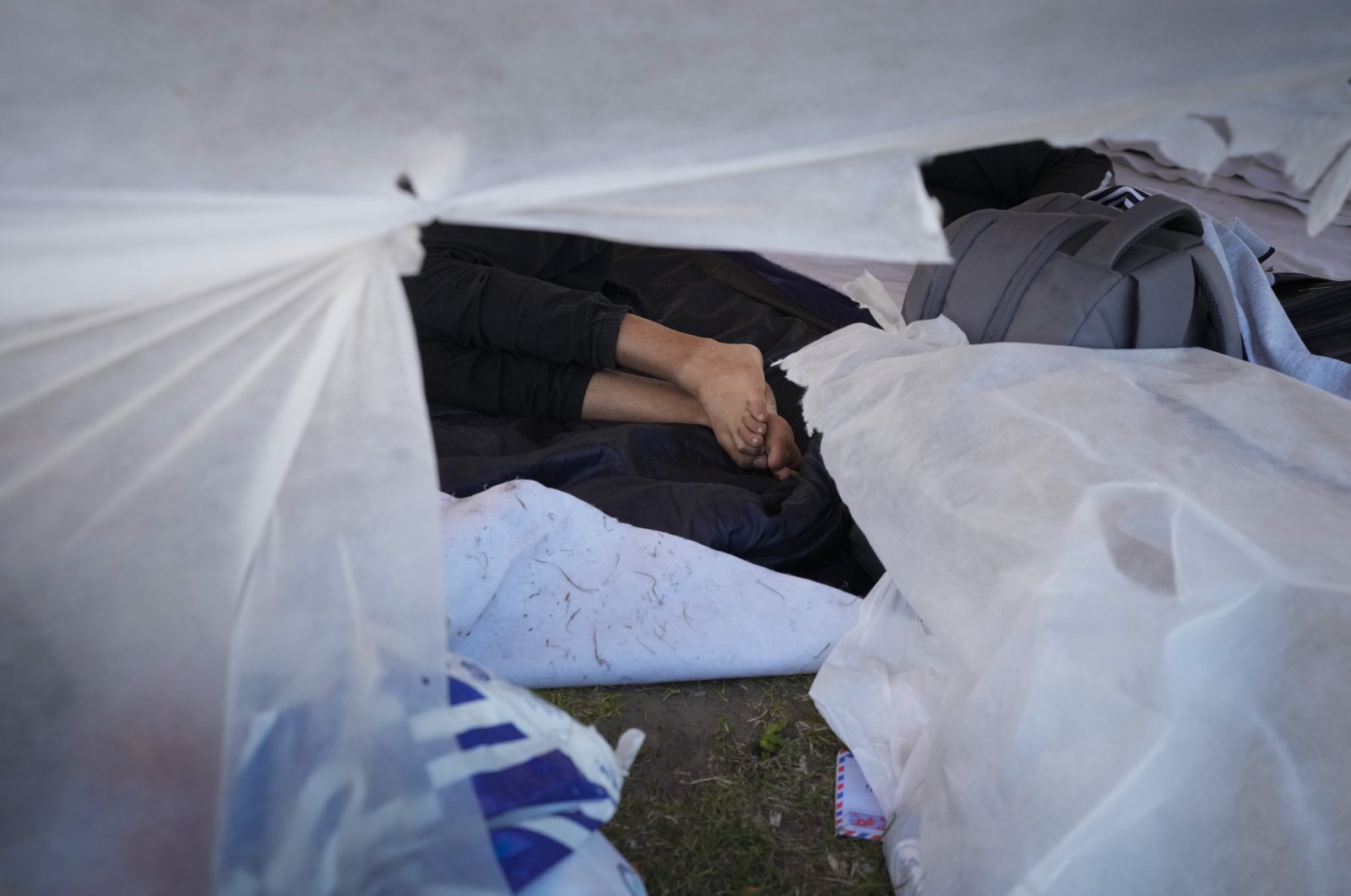 A migrant sleeps amidst hundreds who sought shelter outside an overcrowded asylum-seekers center in Ter Apel, northern Netherlands, Aug. 25, 2022. (AP Photo)