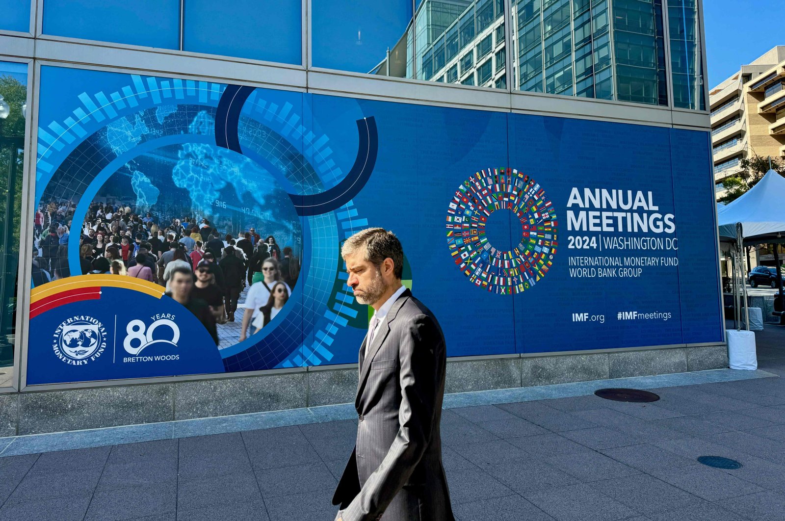 A man walks past signage for the 2024 Annual Meetings of the International Monetary Fund and the World Bank Group, outside of IMF headquarters, Washington, U.S., Oct. 18, 2024. (AFP Photo)