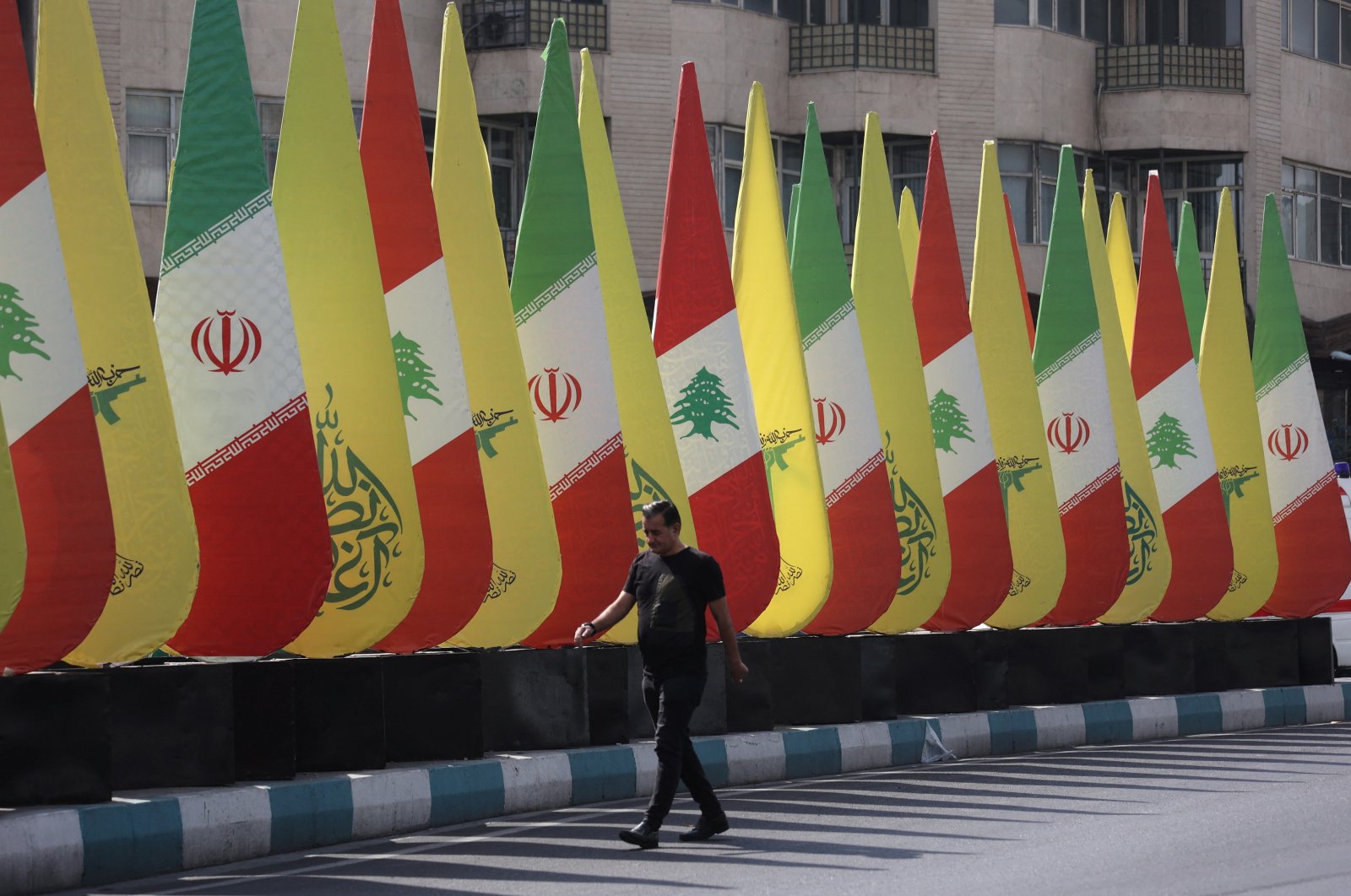 A man walks next to an installation with the flags of Iran, Hezbollah and Lebanon, Tehran, Iran, Oct.18, 2024. (Reuter Photo)