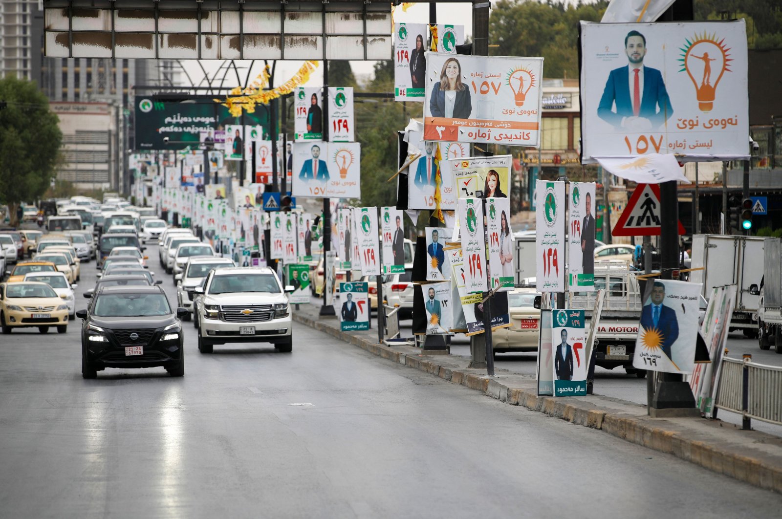 Traffic rolls past electoral campaign posters of candidates ahead of the parliamentary election in the northern Iraqi city of Suleimaniyah, Oct.19, 2024. (AFP Photo)