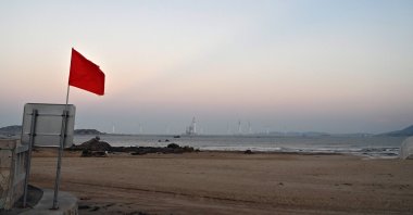 Wind turbines are seen past a red flag at a beach on Pingtan island, the closest point in China to Taiwan’s main island, Oct. 14, 2024. (AFP Photo)
